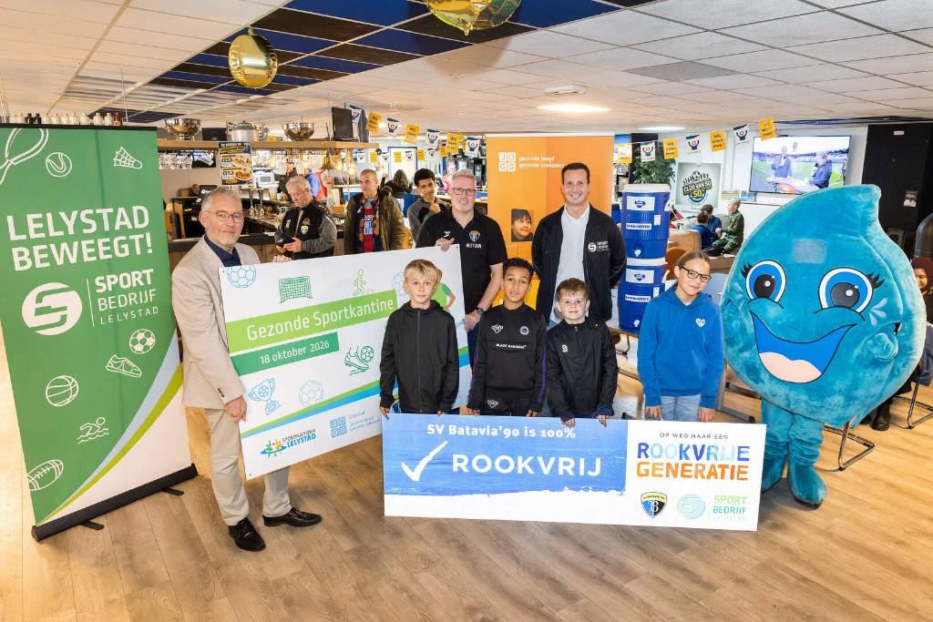 Kinderen en bestuur met het bord Gezonde Sportkantine en de tekst sv Batavia'90 is 100% rookvrij